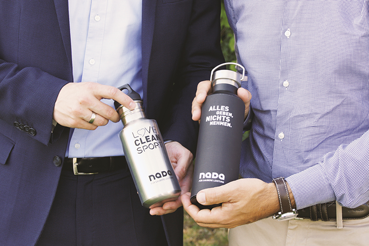 Two male hands each holding a NADA bottle