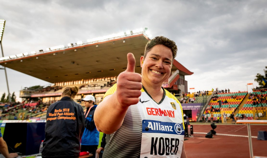Para-Athletin Birgit Kober zeigt im Wettkampfstadion in die Kamera den Daumen nach oben
