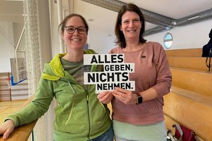 Zuschauer*innen mit Schild in der Hand