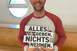 Zuschauer*innen mit Schild in der Hand