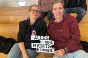 Zuschauer*innen mit Schild in der Hand