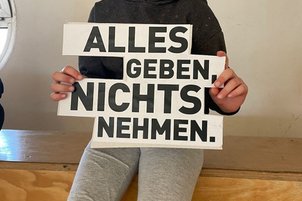 Zuschauer*innen mit Schild in der Hand